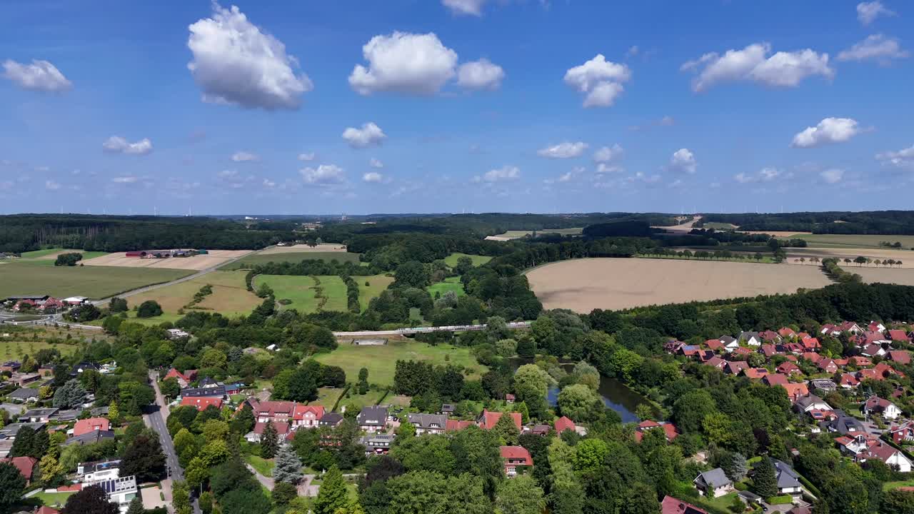 Housing area with single Family houses and lake in suburb. Historic homes and houses in USA. Aerial forward wide shot. Sunny summer day in rural town. Intersection and hills on distance
