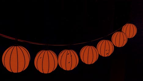 string of red lanterns hanging on a street at night