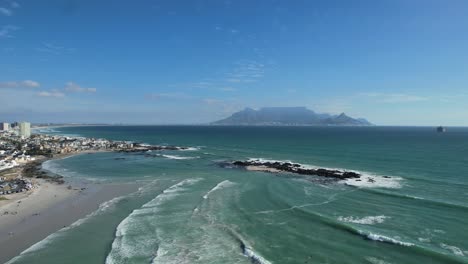 ocean waves and table mountain at big bay beach in cape town, aerial