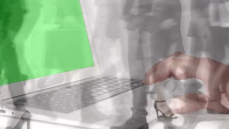 Animation-of-hands-using-laptop-with-green-screen-over-sped-up-commuters-walking-in-modern-building