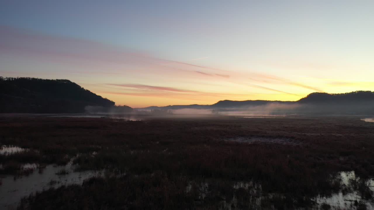 amanecer brumoso sobre un paisaje de humedales