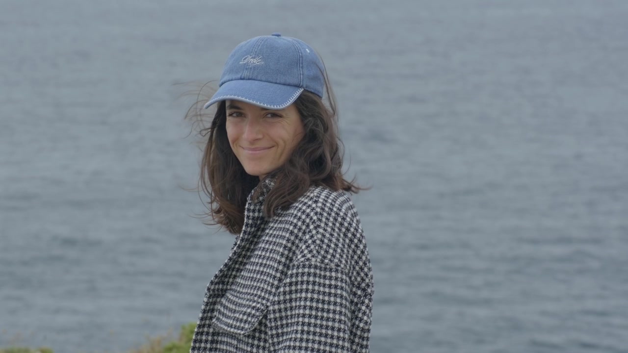 Smiling woman by the ocean with hair moving gently in the wind