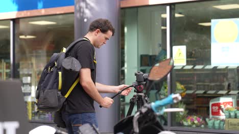 Un-Joven-Caucásico-Con-Una-Cámara-En-Un-Trípode-Camina-Y-Se-Instala-Solo-En-Las-Calles-De-Londres-A-Fines-Del-Verano