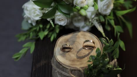 beautiful wedding rings lie on wooden stand with wedding bride's bouquet