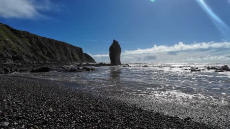 Full-tides-with-gentle-waves-and-immense-sea-stack-on-shingle-beach-Ballydwane-Waterford-Ireland