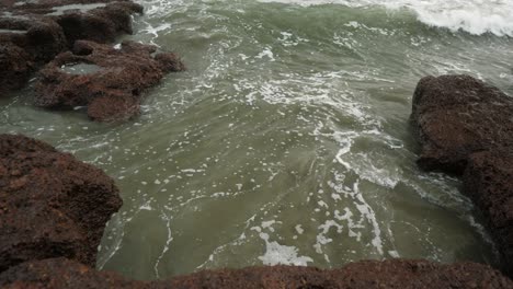 waves crash against a rocky shoreline on an overcast day, creating a dynamic interplay between the water and rugged rocks