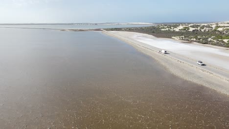 Avión-Teledirigido-Sobre-El-Lago-Natural-Y-Rosado-Macdonnell-Y-Dunas-De-Arena-En-El-Sur-De-Australia-Con-Automóviles-Circulando-Por-La-Carretera