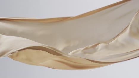 animation of cream fabric blowing with copy space over white background