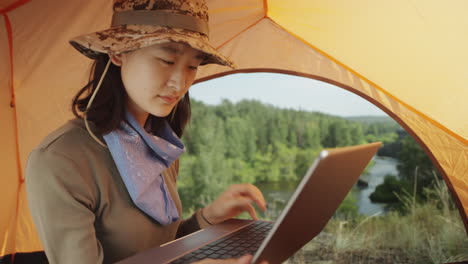 asian female tourist using laptop in tent