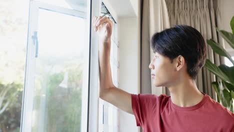 young asian male looking out window with thoughtful expression, copy space