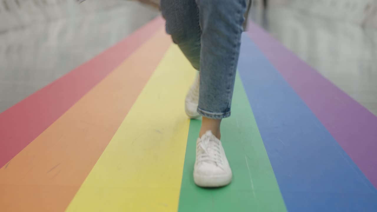 gen z gay alegría diversión caminar vista de bajo ángulo con zapatillas blancas y vaqueros.