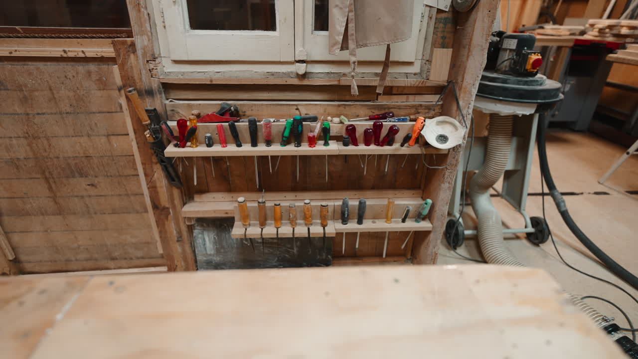 Collezione di scalpelli per legno e cacciaviti organizzati su una rastrelliera di legno in un laboratorio