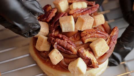 donut de caramelo siendo decorado con cubos de caramelo vista superior