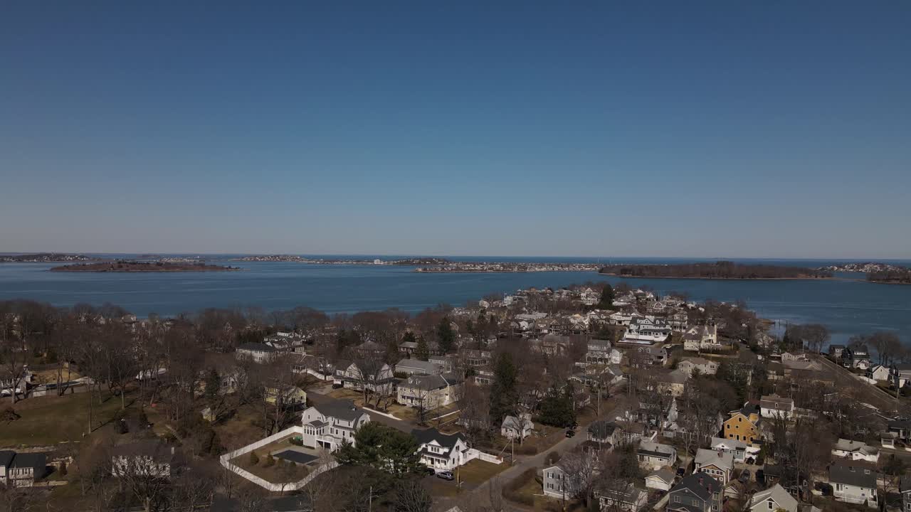 un dron ascendente revela casas en una comunidad residencial, islas, puertos y una ciudad vecina.