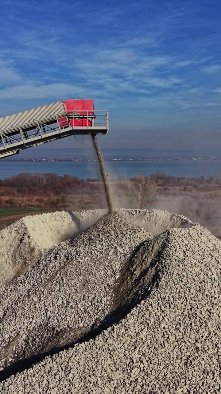 Operazioni di cava che mostrano un nastro trasportatore e un cumulo di pietre vicino all'acqua