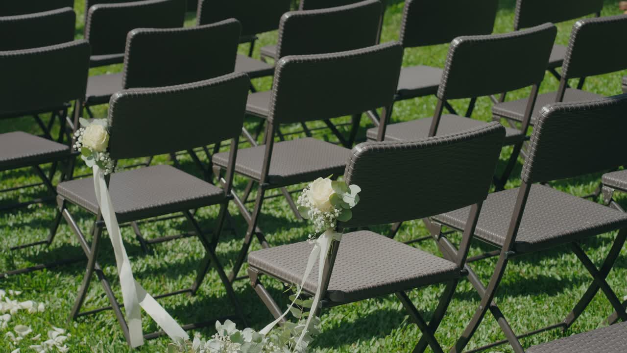 Rows of outdoor wedding chairs with white rose decorations