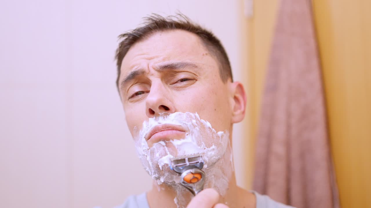 남자 가 욕실 에서 수염 을 면도 하고 있다