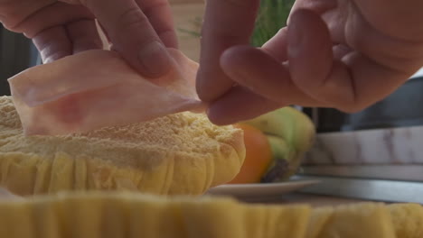 Die-Person-Legt-Zum-Frühstück-Schinken-Auf-Halbiertes-Croissantbrot