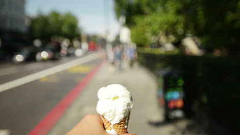 man holding ice-cream point of view walking through city