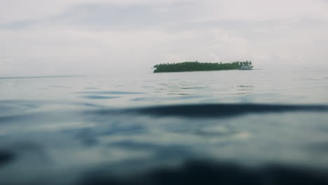 Plácidas-Y-Tranquilas-Aguas-Del-Océano-Con-Una-Pequeña-Isla-A-Lo-Lejos,-En-ángulo-Bajo