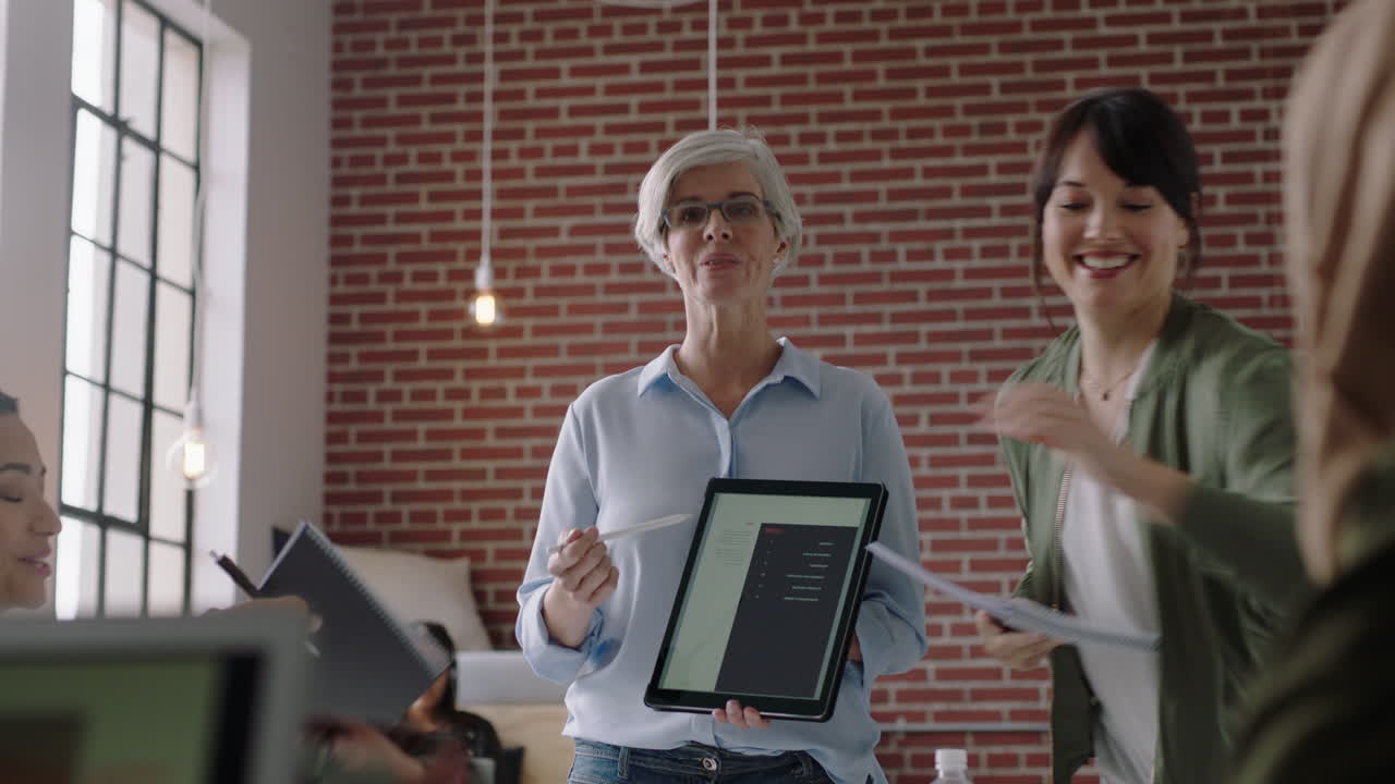 uomini d'affari che si incontrano brainstorming team manager donna che presenta idee di marketing per un progetto di avvio utilizzando un tablet discutendo di strategia colleghi che lavorano insieme in ufficio presentazione