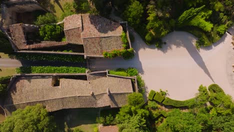 top-down drone view of château de castille, its entrance with two roman pavilions surrounded by lush greenery, and its french formal garden