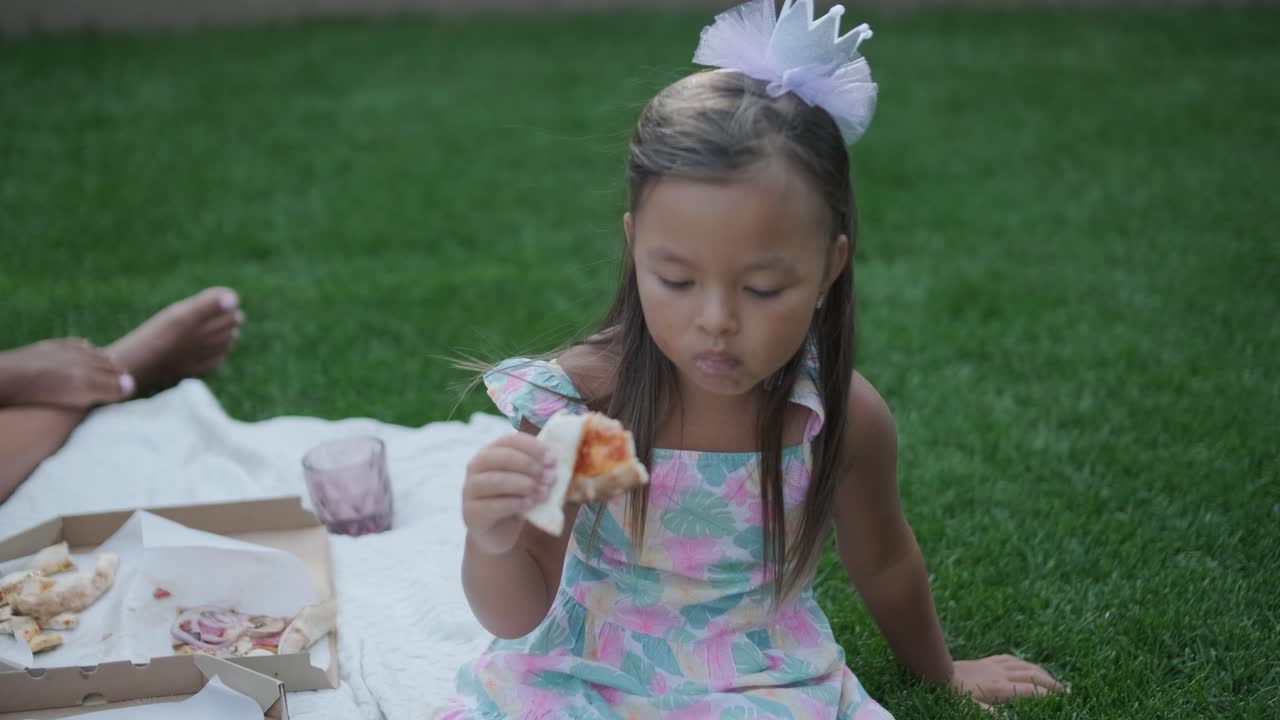 una madre y su hija pequeña se sientan en una manta en el patio trasero, participando en una actividad de dibujo juntos. la escena al aire libre captura un momento familiar pacífico, fomentando la creatividad y el vínculo.