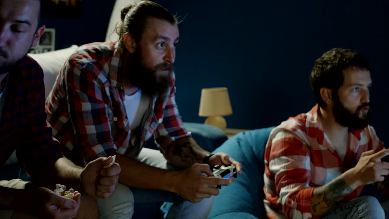 hombres jugando con gamepads en casa