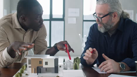 multiethnic male architects discussing building model