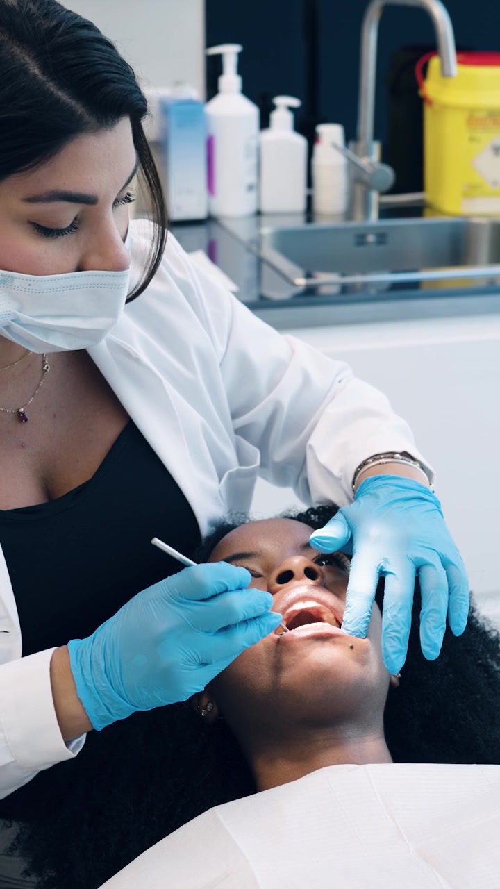 Dentista Examinando Dentes de Paciente em Clínica Odontológica Moderna