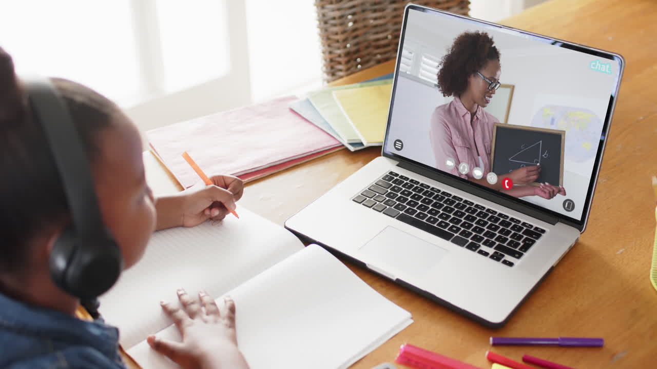 niña afroamericana usando una computadora portátil para una lección en línea con una maestra afroamericana en la pantalla