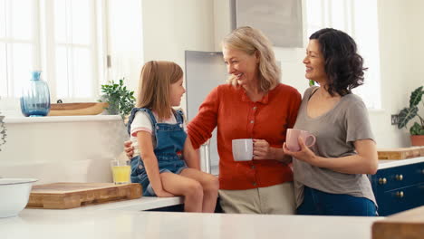Same-Sex-Family-With-Two-Mature-Mums-And-Daughter-Sitting-In-Kitchen-Talking-Together