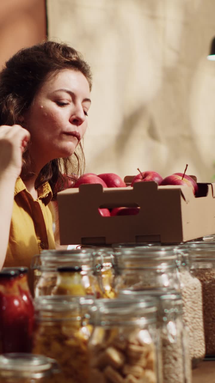 Vídeo vertical de una mujer añadiendo manzanas ecológicas a una cesta en una tienda