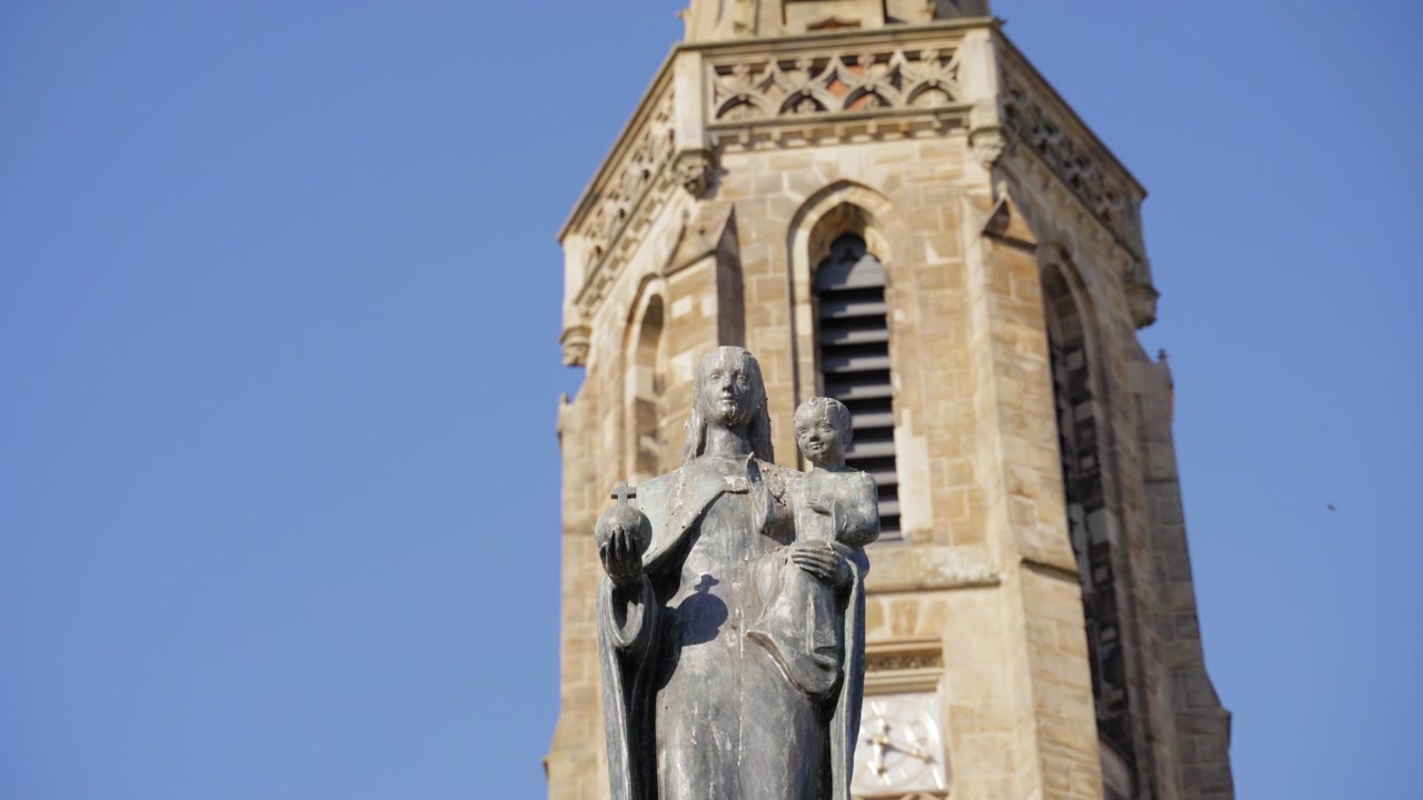 Vista ravvicinata di una storica statua religiosa davanti alla torre di pietra della Chiesa di San Luigi a Saarlouis, Germania.