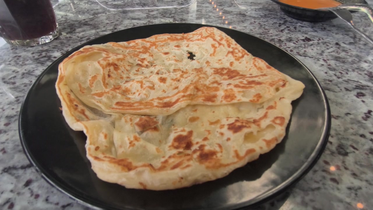 Sepotong roti canai klasik disajikan di piring dengan kari dhal gurih. Ini melambangkan persiapan dasar dan pokok hidangan tersebut di Malaysia. Hidangan ini tetap sangat populer untuk sarapan.