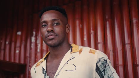 man in stylish shirt in front of red bamboo wall