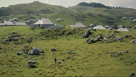 una foto de un dron de la velika planina, un excursionista caminando por el prado verde