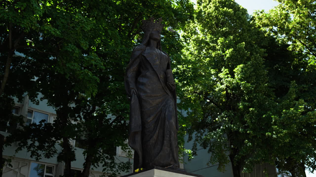 Statue of Queen Maria of Romania standing tall in Chișinău, Moldova. A historic monument honoring royal heritage, set in a peaceful public square with cultural and national significance