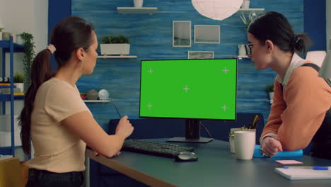 Two-collegues-working-together-on-computer-with-mock-up-green-screen-chroma-key-display