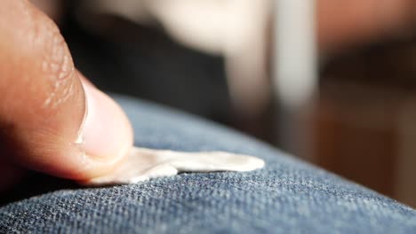 close-up of a person removing a small white object from blue jeans