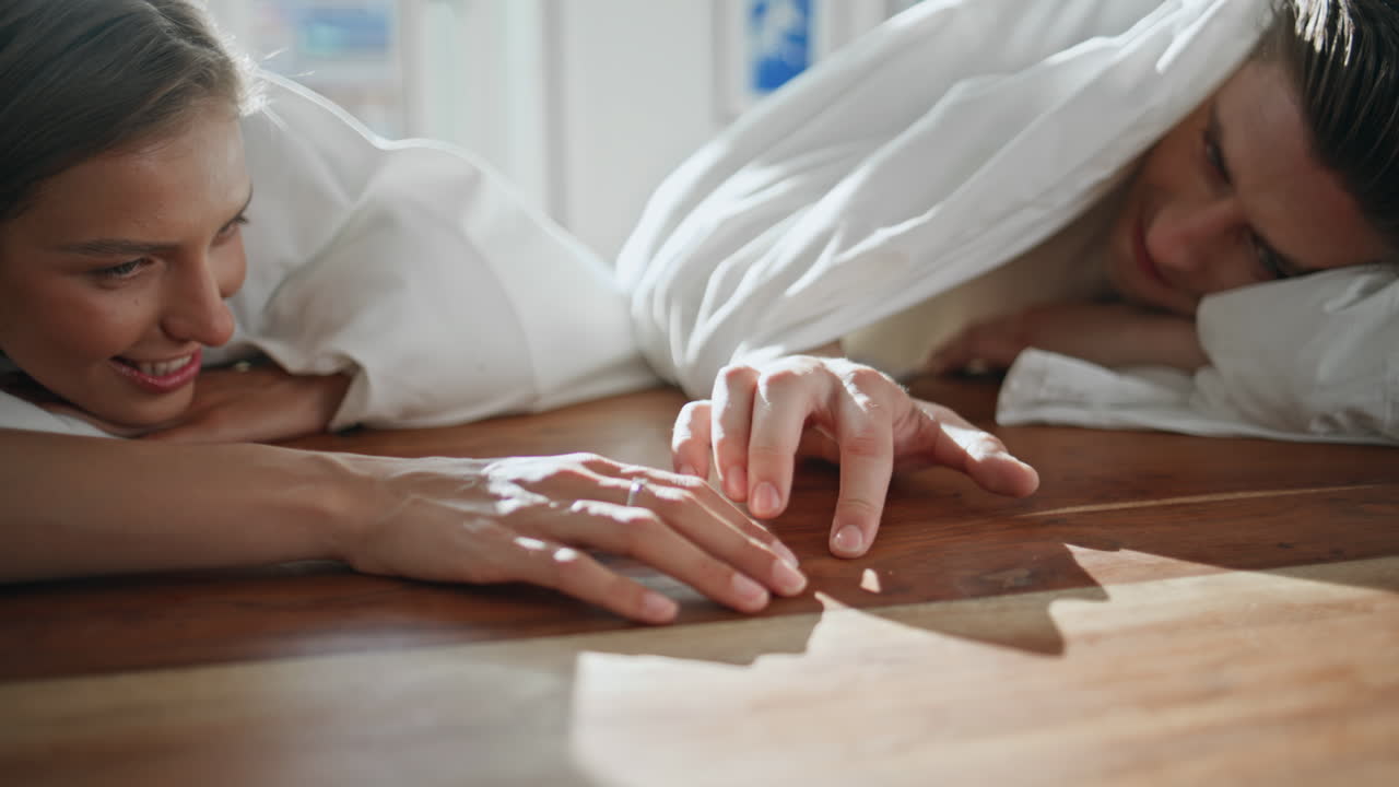 Tender lovers touching hands in sunlight closeup. Playful couple lying blanket
