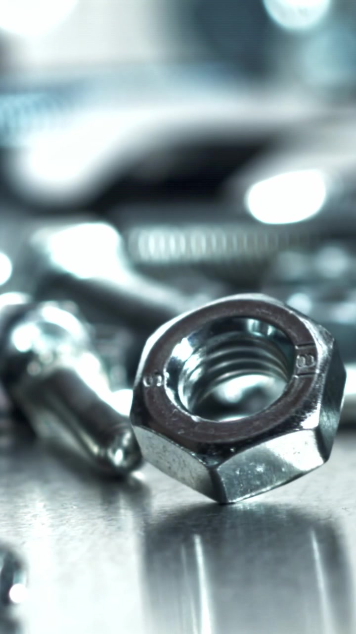 Close-up of a Metal Nut Rotating on a Reflective Surface