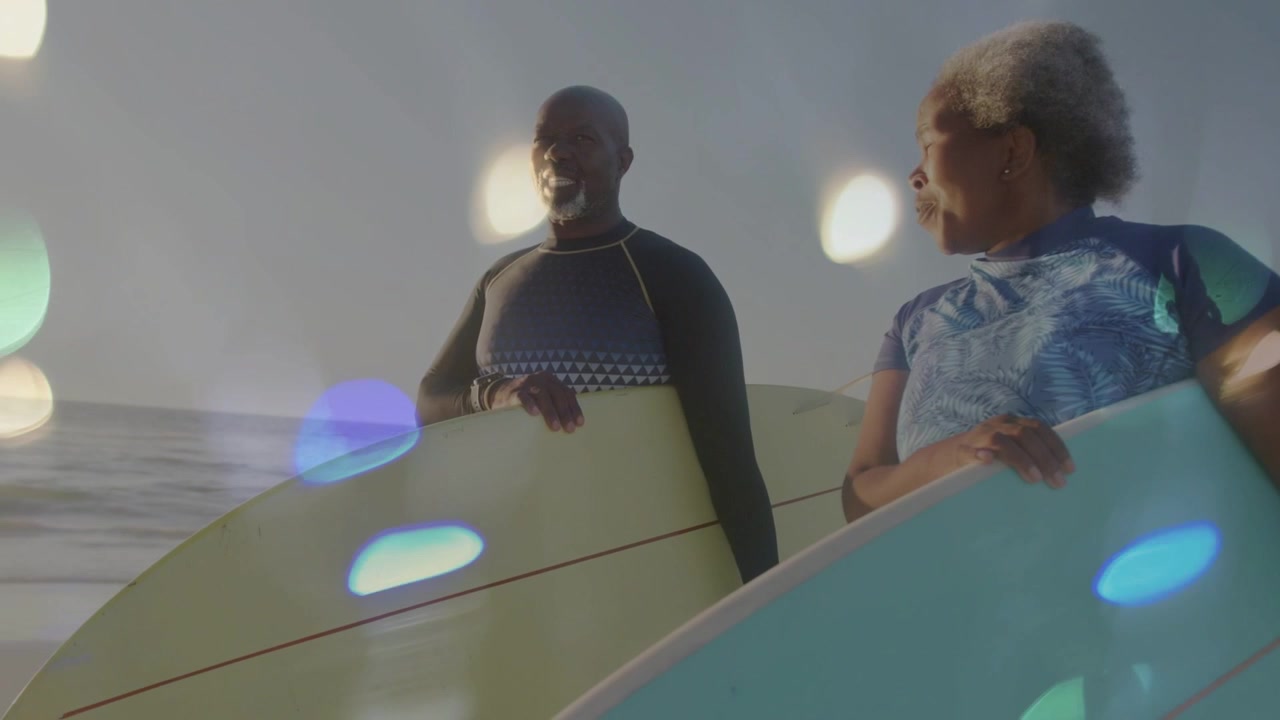 Donna matura con tappetino che guida la famiglia nella preparazione al surf per il benessere in spiaggia, mentre la telecamera esegue una panoramica, con bokeh sui volti.