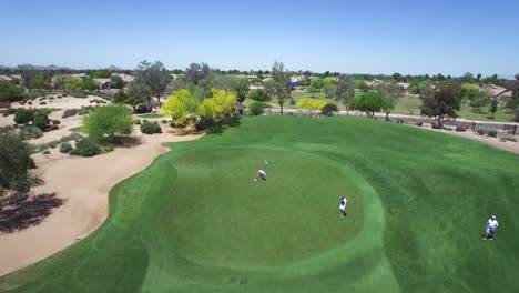 Aerial-golfer-in-orange-shorts-putts-as-a-drone-flies-over,-Scottsdale,-Arizona
