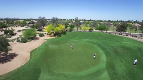 aerial golfer in orange shorts putts as a drone flies over, scottsdale, arizona