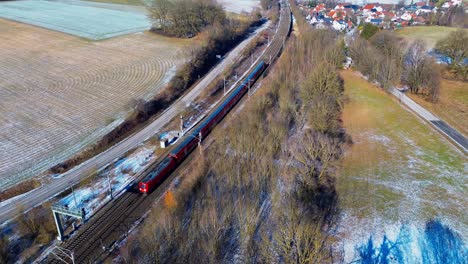 tren de pasajeros rojo navegando a través de un paisaje rural helado