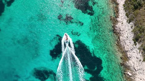 Small-boat-taking-passengers-through-clear-turquoise-water-to-a-hidden-beach,-in-the-islands-of-Croatia