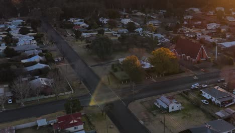 drone camera glides over suburban homes and streets in coonabarabran, new south wales, during golden hour with warm, soft sunlight and gentle movement