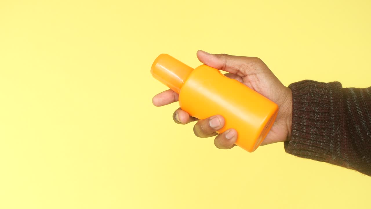 una mano sosteniendo una botella de protector solar