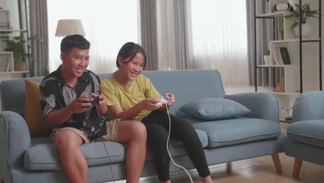 funny asian children with joystick game playing video games at home